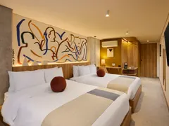 Suite Doble with two double beds beneath a blue and ochre line mural