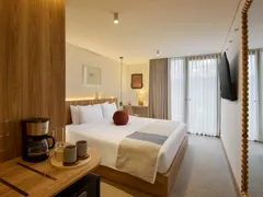Suite King with a King bed, coffee maker and a wooden mirror by the window